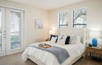 A bedroom with a white bed and a tray of food on it.