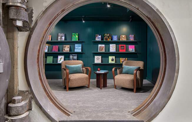 A room with a circular window and two chairs.