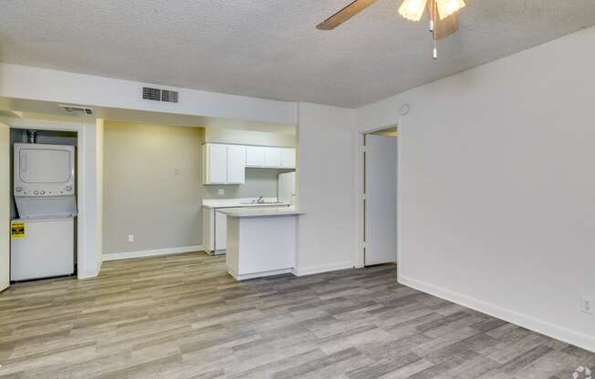 the living room and kitchen of an apartment with a washer and dryer