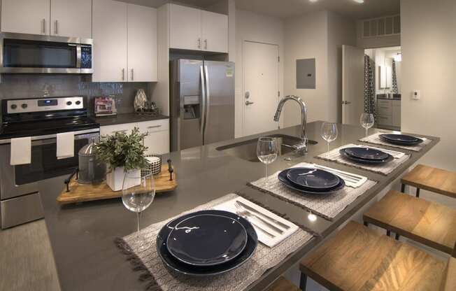 a large kitchen with stainless steel appliances and a table with plates and chairs