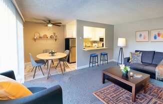 A living room with a grey couch, a coffee table, and a dining table with chairs.