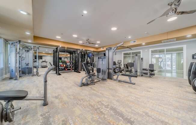 the spacious fitness center with weights and cardio equipment at the whispering winds apartments in pearland,