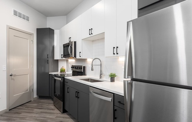 A modern kitchen with a stainless steel refrigerator and black cabinets.