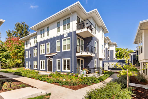 A blue and white two story apartment building with a balcony on the second floor.