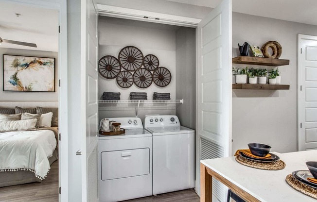 a white washer and dryer in a laundry room with a bed