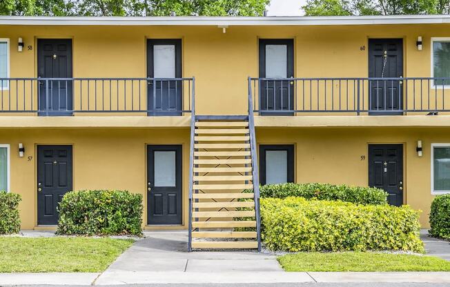 the front of a yellow building with stairs and balconies