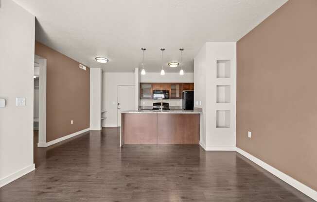 an empty living room with a kitchen in the background