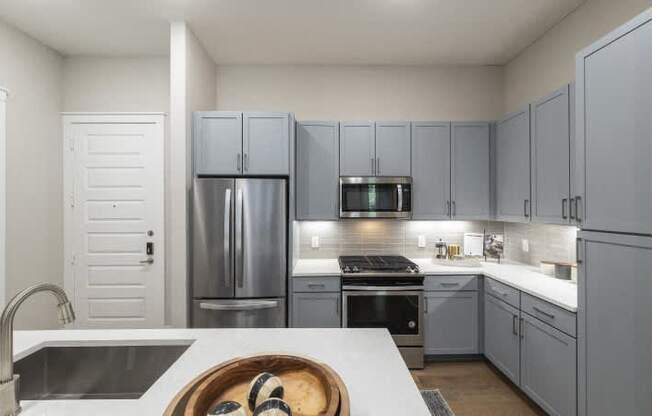A modern kitchen with a white countertop and grey cabinets.