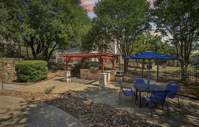 A red pavilion is surrounded by trees and chairs.