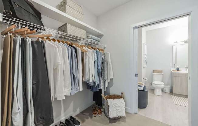 A white closet with clothes and shoes.