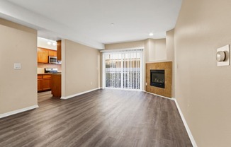 an empty living room with a fireplace and a kitchen