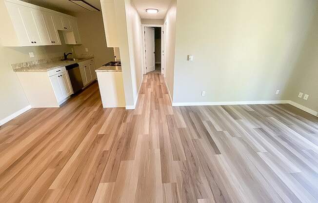 A kitchen with white cabinets and a wooden floor.