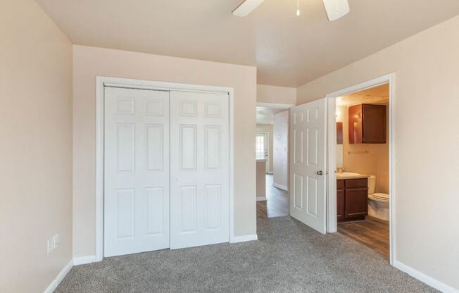 Bedroom with en-suite bathroom, closet, and ceiling fan
