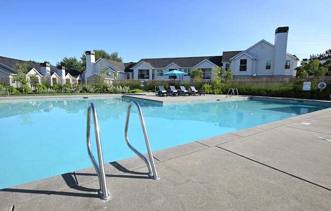 A swimming pool with a diving board in front of a residential area.