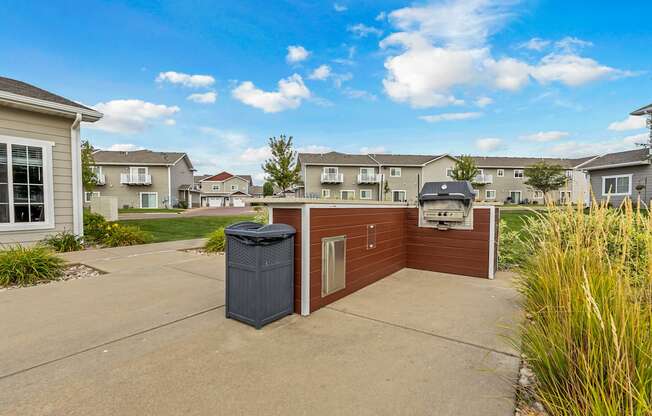 A residential area with a brown house and a grey trash bin.