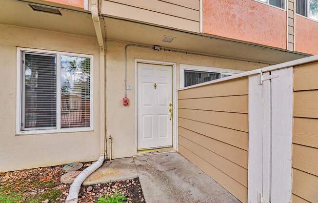 A white door is on the right side of a tan building.