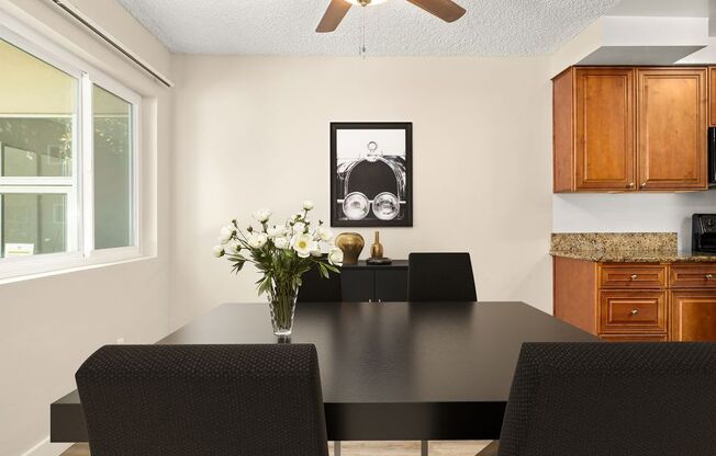 a dining room with a table and chairs and a vase of flowers