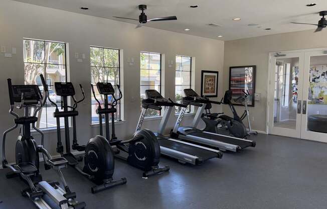 A spacious gym with a variety of exercise equipment and a ceiling fan.