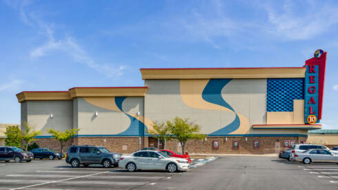 an old movie theater with cars parked in a parking lot