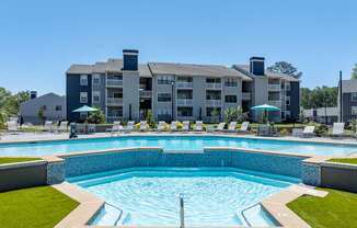 A large swimming pool in front of a multi-story apartment building.