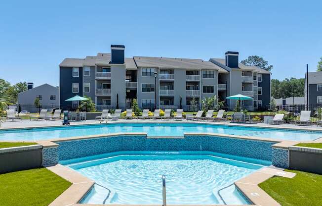A large swimming pool in front of a multi-story apartment building.