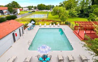 A large swimming pool surrounded by lounge chairs and umbrellas.