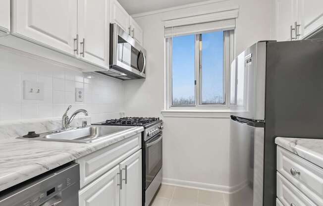 A kitchen with white cabinets and appliances.