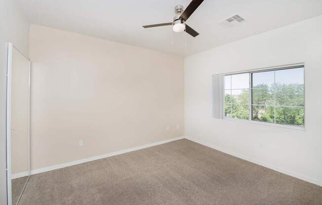 Empty room with a ceiling fan and a window.
