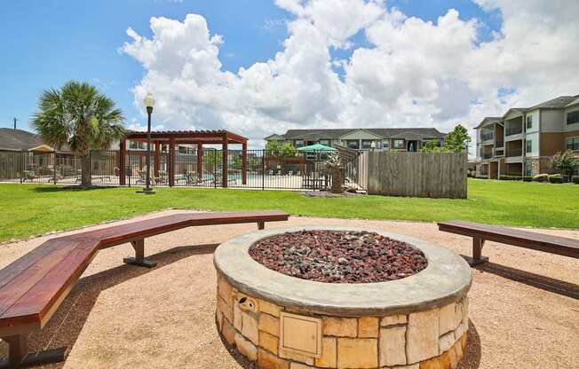 A fire pit in the middle of a playground with benches around it.