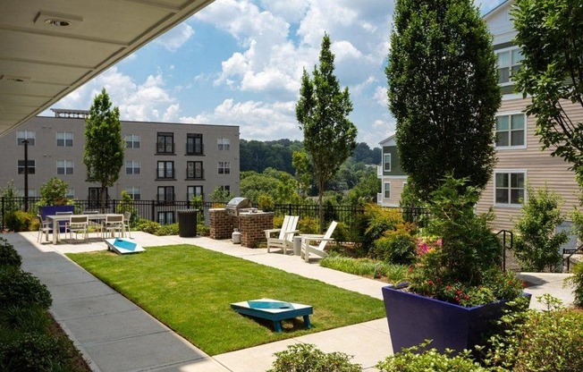 a patio with a lawn and tables and chairs in a courtyard