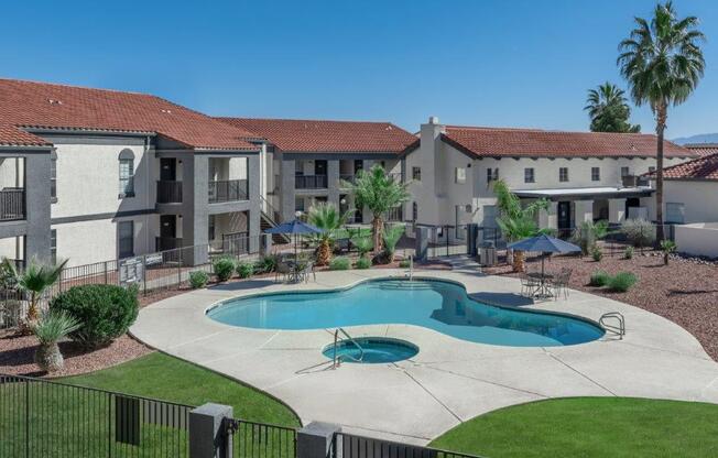 A swimming pool in front of a building with a black fence around it.