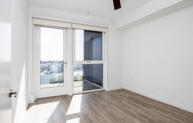 an empty living room with a door to a balcony