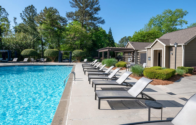 Wynnwood Vinings resident swimming pool with chaise lounge chairs and trees in the background