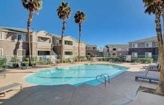 A swimming pool surrounded by palm trees and apartment buildings.