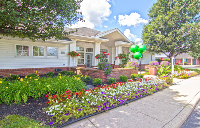 the front yard of a house with flowers and a sidewalk