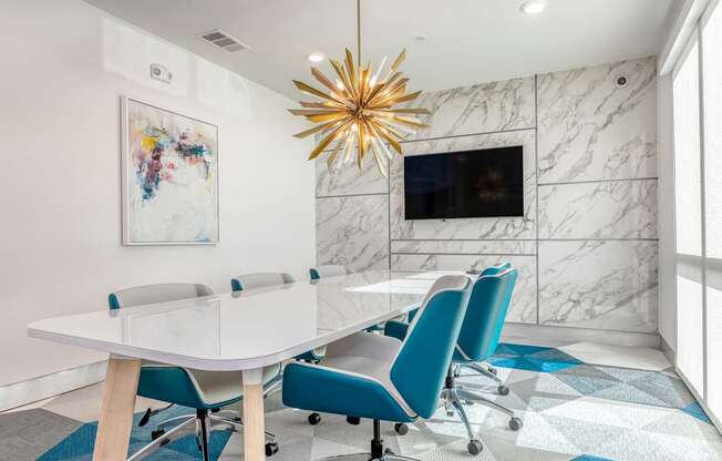 A modern conference room with a white table and blue chairs.