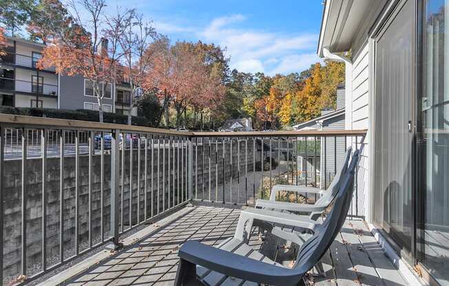 a patio with two chairs and a railing on a balcony