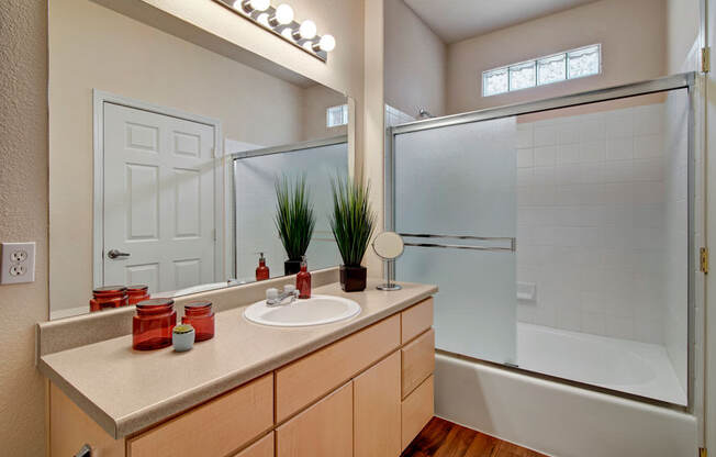 A bathroom with a sink, mirror, and shower.