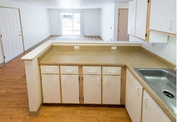 A kitchen with white cabinets and a wooden floor.