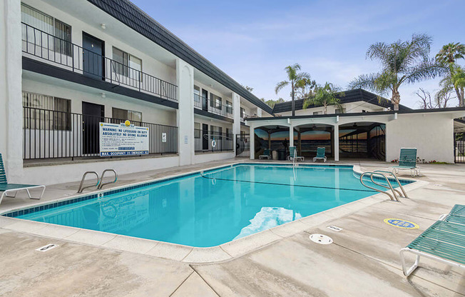 Community Swimming Pool with Pool Furniture at Palmilla Apartments located in San Diego, CA.