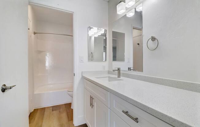 A white bathroom with a sink, mirror, and shower.