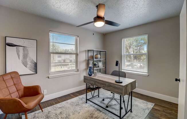 a home office with a desk and a ceiling fan