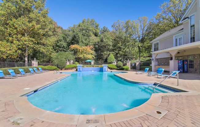 A large outdoor swimming pool surrounded by trees and lounge chairs.