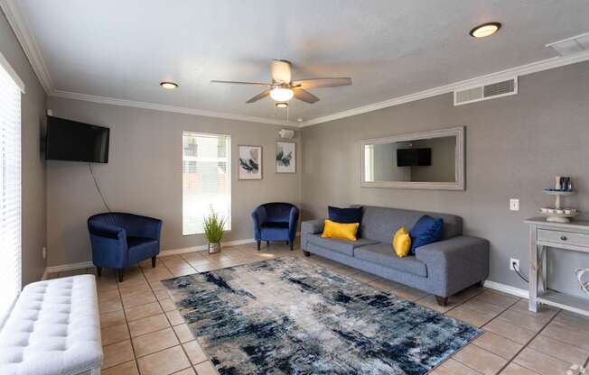 A living room with a grey couch, blue chairs, and a white ottoman.