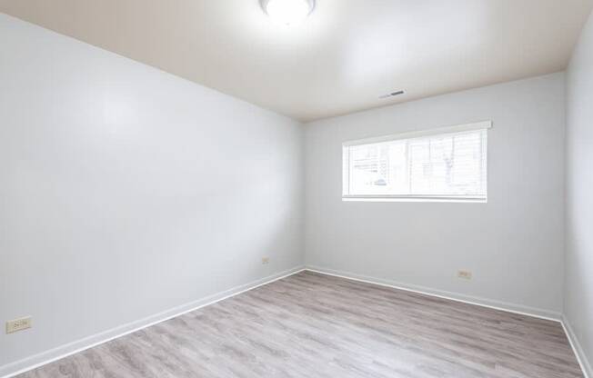 A room with a window and a wooden floor.