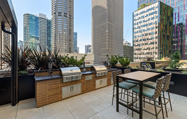 a rooftop patio with a grill and a table and chairs