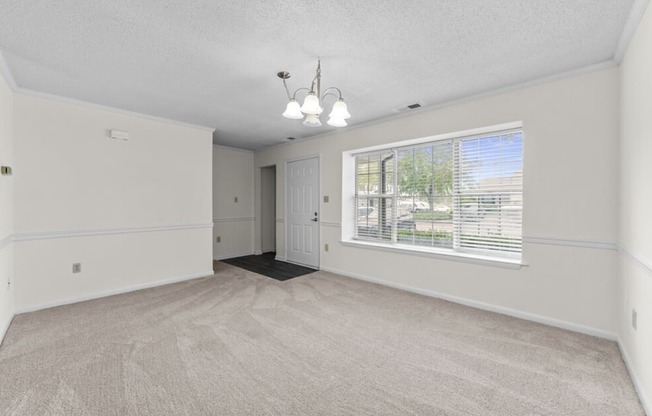 an empty living room with a large window and white walls