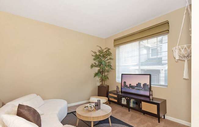 A living room with a white couch, a wooden coffee table, and a television on a wooden stand at The Landing Apartments and Townhomes, Oregon, 97045
