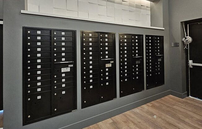 A wall of black mailboxes with white labels on them.