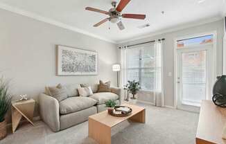 A living room with a grey couch, a coffee table, and a ceiling fan.